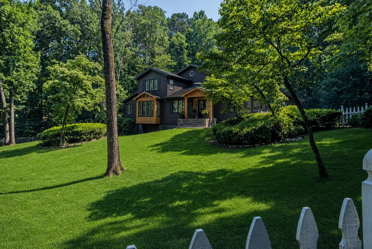 Black and warm wood woodland home surrounded by a green lawn and mature trees